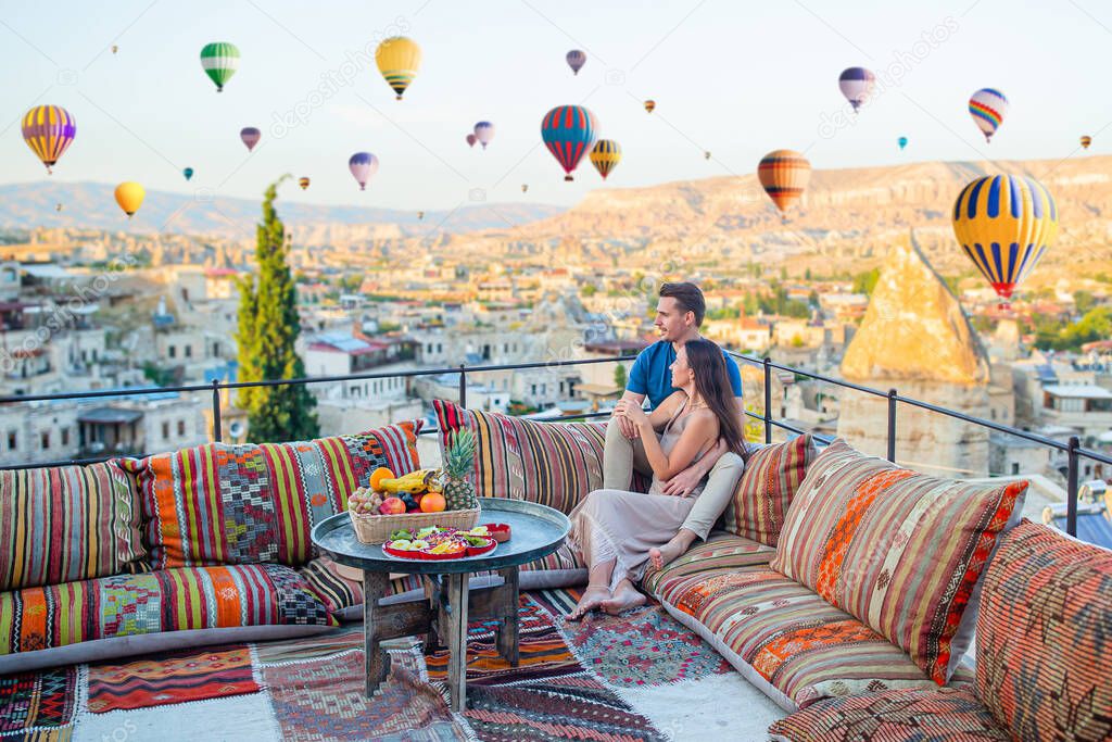 Happy couple in Cappadocia in outdoor cafe. Couple travels the world. Hot air balloon flights.