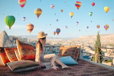 Güneş doğarken Kapadokya, Türkiye 'de sıcak hava balonları seyreden mutlu genç kadın
