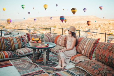 Güneş doğarken Kapadokya, Türkiye 'de sıcak hava balonları seyreden mutlu genç kadın