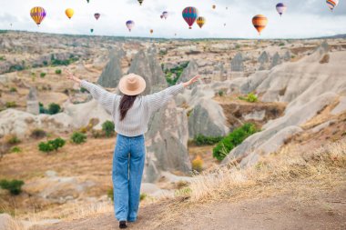 Güneş doğarken Kapadokya, Türkiye 'de sıcak hava balonları seyreden mutlu genç kadın