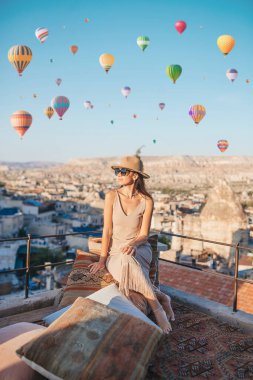 Güneş doğarken Kapadokya, Türkiye 'de sıcak hava balonları seyreden mutlu genç kadın
