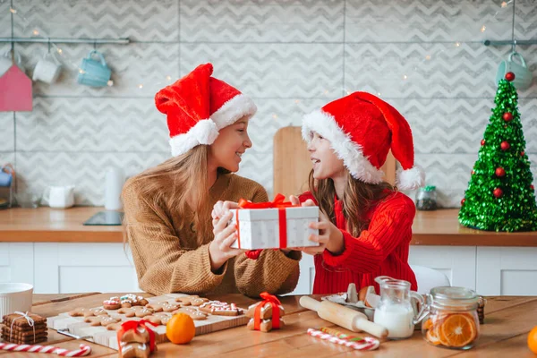 Kleine Mädchen basteln Weihnachts-Lebkuchenhaus am Kamin im geschmückten Wohnzimmer. — Stockfoto