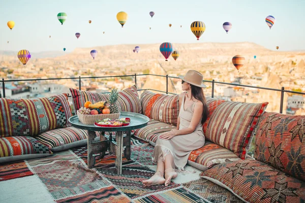 Güneş doğarken Kapadokya, Türkiye 'de sıcak hava balonları seyreden mutlu genç kadın