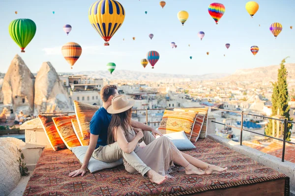 Glückliches junges Paar bei Sonnenaufgang beim Beobachten von Heißluftballons in Kappadokien, Türkei — Stockfoto