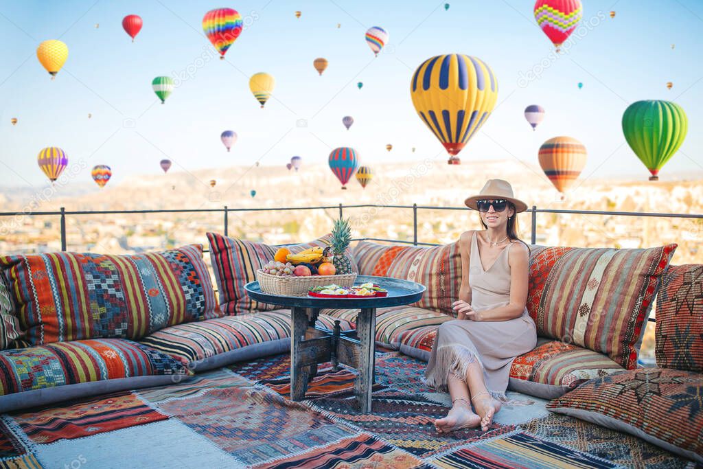 Happy young woman during sunrise watching hot air balloons in Cappadocia, Turkey