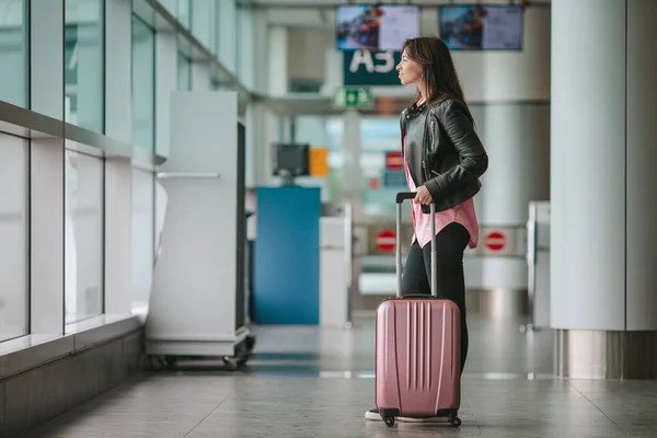 Young woman with baggage in international airport walking with her luggage. Airline passenger in an airport lounge waiting for flight aircraft