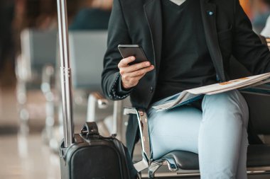 Man with smart phone - young businessman with baggage in airport.