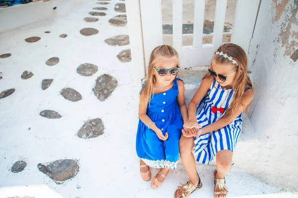 Little happy girls on Mykonos Island have fun on the street