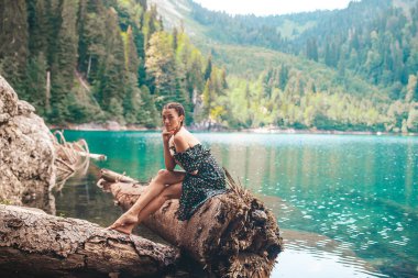 Beautiful girl with a picturesque view of the mountains and the lake in the reserve
