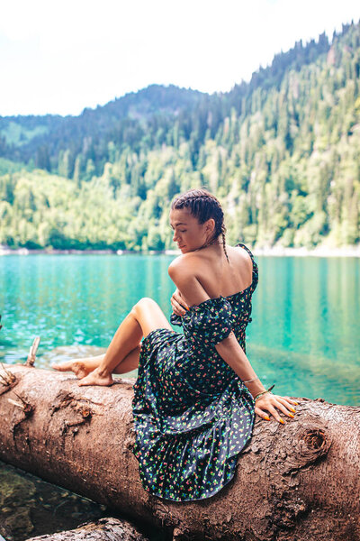 Beautiful girl with a picturesque view of the mountains and the lake in the reserve