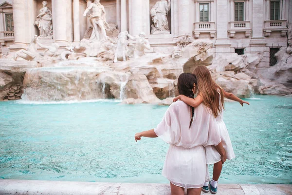 Mother and daughter enjoy the Trevi Fountain, Rome, Italy. Happy family making a wish to come back.
