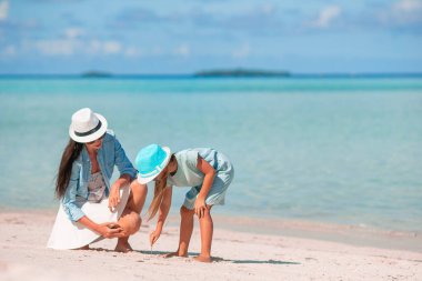 Young happy mother and her adorable little daughter on tropical beach
