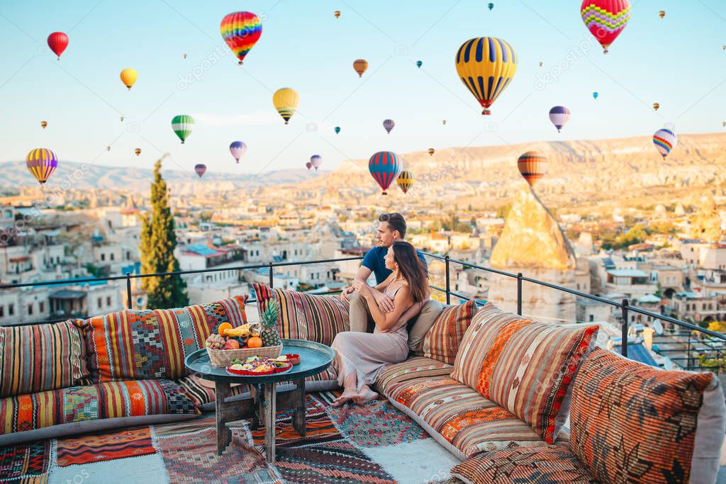 Happy couple on vacation in Cappadocia with hot air balloons in the background. Hot air balloon flights.