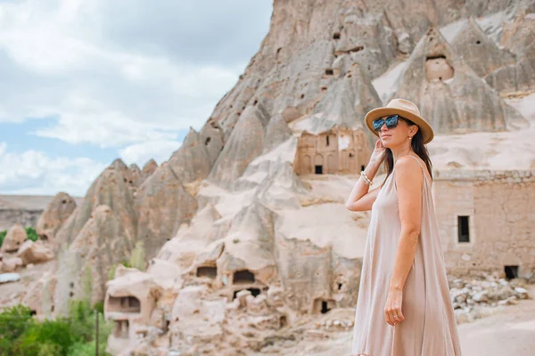 Young woman on background of ancient cave formations in Cappadocia, Turkey. The Monastery is one of the largest religious buildings.