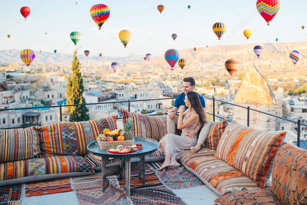 Happy couple on vacation in Cappadocia with hot air balloons in the background. Hot air balloon flights.