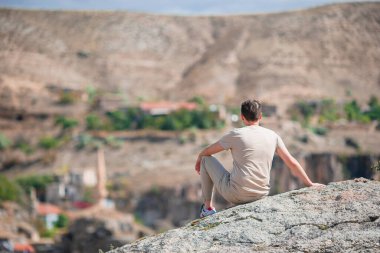 Young man with air balloons in the background in the sky in Goreme in Cappadocia, Turkey