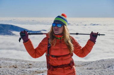Kış sporu kıyafetleri ve yürüyüş direğiyle gezen kadın bulutlarla dolu bir vadiye bakıyor. Romanya 'nın Karpat dağlarında kış faaliyetleri. Portre, başarı, amaç.