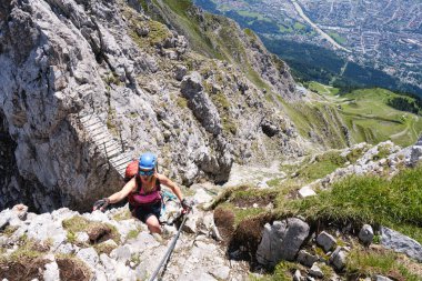 Innsbruck 'un yukarısında, Ferrata Klettersteig üzerinden Nordkette' de açıkta kalan bir kadın turist. Tahta köprü, aktif, dağcılık.