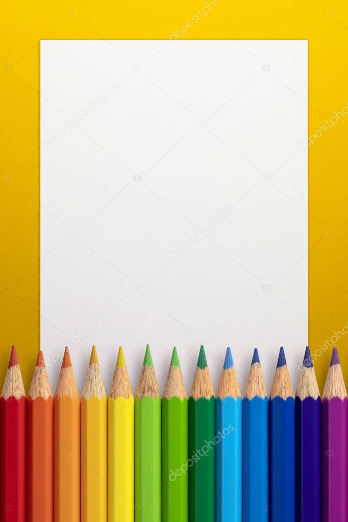 Vertical frame made of color pencils and white paper on an yellow background.
