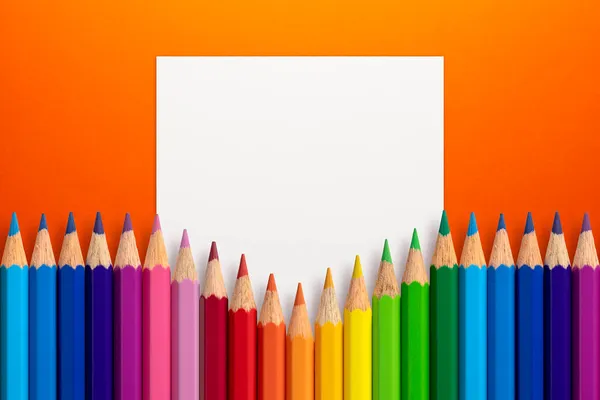 ホワイトペーパーカードノートとオレンジの紙の背景に色鉛筆で作られた創造的なレイアウト 平置きだ 教育理念 — ストック写真