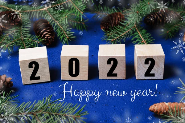 Happy new year 2022 banner with christmas tree branches and snowflakes, numbers 2022 on wooden cubes, christmas winter background