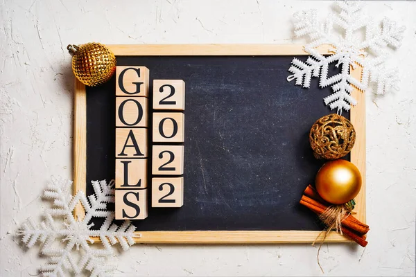 Targets 2022 black writing board, wooden cubes with inscription. Copy space in the center. Christmas balls and snowflakes frame.