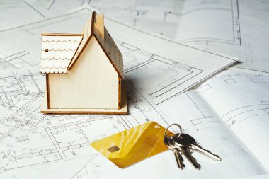 Kağıt yüzey üzerinde ahşap bir ev, cereyan ve birkaç anahtarla. Konsept - anahtar ev yapmak, kira ödemek veya satmak