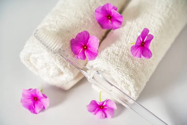 Brosse à dents et serviettes blanches, fleurs roses aromathérapie. Soins buccodentaires, hygiène corporelle et routines quotidiennes matinales. — Photo