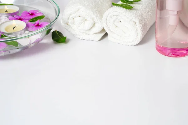 Forniture per la cura del corpo, asciugamano bianco, olio e fiori di rosa su uno sfondo bianco, posto per il testo — Foto Stock
