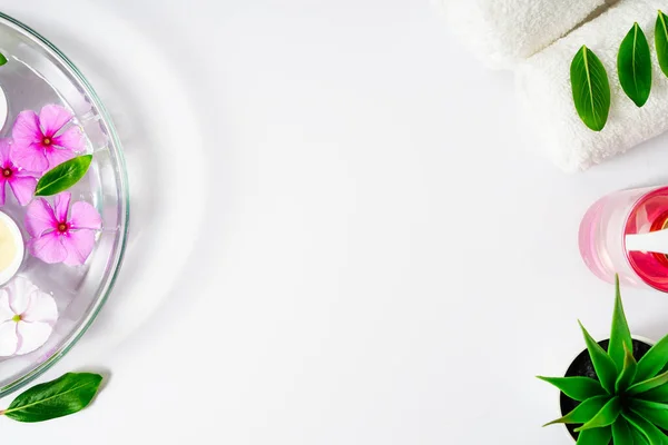 Materiales para el cuidado del cuerpo, toalla blanca, aceite y flores de rosas sobre un fondo blanco, lugar para el texto —  Fotos de Stock