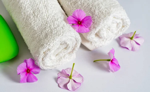 Serviettes roulées blanches propres avec des fleurs et du savon vert sur blanc — Photo