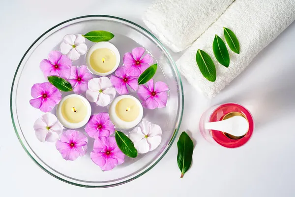 Körperpflege, weißes Handtuch, Öl und Rosenblüten auf weißem Hintergrund, brennende schwimmende Kerzen in einer Schüssel mit Wasser, Wellness-Entspannung und Meditation — Stockfoto