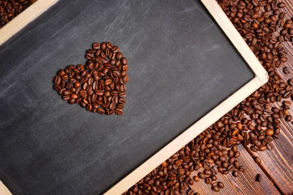 Des grains de café en forme de cœur sur un tableau noir, un amoureux des fleurs pour la Saint-Valentin — Photo