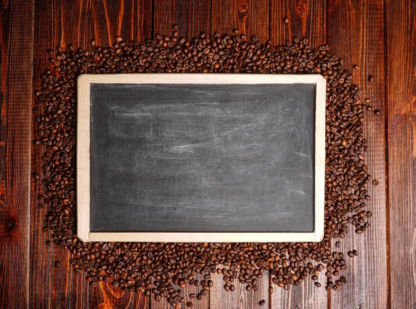 Moldura modelo vazio feito de grãos de café. Fundo de madeira placa preta com sementes de café e espaço de cópia — Fotografia de Stock