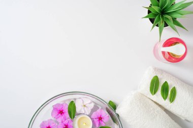Hassas bir arka plan, özel hijyen jeli, beyaz havlular ve aromaterapi için pembe çiçekli bir kap. Boşluğu kopyala.