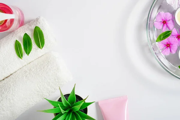 Sfondo delicato, gel igienico intimo, asciugamani bianchi e un contenitore con fiori rosa per l'aromaterapia. Copia spazio. — Foto Stock