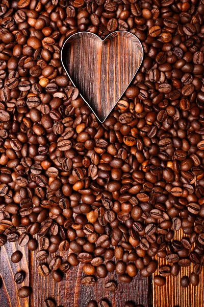 空旷的心形由咖啡豆背景制成。平躺在床上爱的象征咖啡。垂直木制壁纸 — 图库照片