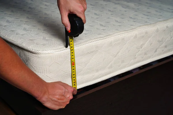 Measuring the height of the mattress with a measuring tape. Comfortable sleep orthopedic bed.