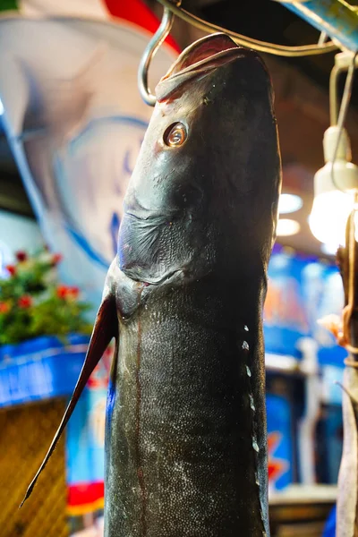 Auf einem Fischmarkt hängt ein Fischkopf an einem Haken. Meeresfrüchte frischer roher Fisch als gesundes Produkt — Stockfoto