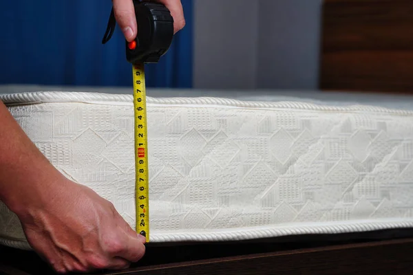 Measuring the height of the mattress with a measuring tape. Comfortable sleep orthopedic bed.