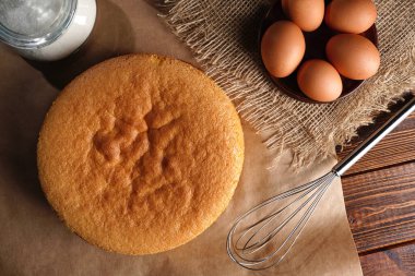 Tahta bir masa, un ve yumurta malzemelerinin üzerine ev yapımı mükemmel sünger keki.