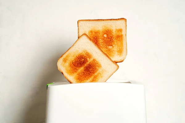 Tostadora con rebanadas de pan. Tostadora eléctrica con dos rebanadas de pan caliente de cerca sobre fondo blanco. — Foto de Stock