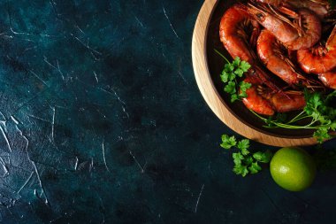 Izgarada pişmiş Arjantin karidesleri, otlu Langoustines, koyu bir arka planda sarımsak ve limon.