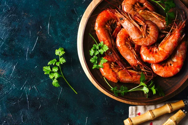 Gegrilde gekookte Argentijnse garnalen, garnalen langoustines met kruiden, knoflook en citroen op een donkere achtergrond, bovenaanzicht — Stockfoto