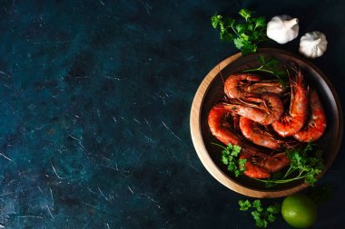 Izgara Arjantin karidesleri, karides langoustines otlu, sarımsak ve limonlu koyu bir arka plan, üst manzara