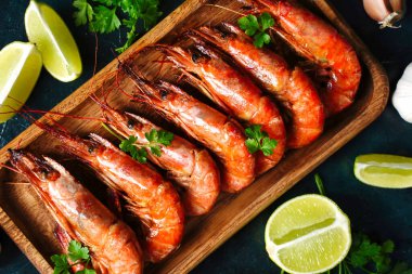 siyah yüzeyi düzenlenmiş baharatlar ile plaka üzerinde ızgara karides ve limon parçaları Üstten Görünüm