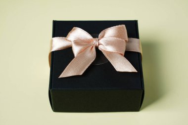 Koyu renk hediye paketi, kurdeleli ve sarı arka plan üst görünüm fotokopi alanı üzerinde. Tatil geçmişi düzdü. Doğum günü hediyesi, 8 Mart, Anneler Günü, Sevgililer Günü. Erkekler için tebrikler.