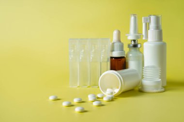 Burun damlası ve burun için sprey ya da soğuk algınlığını tedavi etmek için bir hap. Yeşil arka planda ilaç ve renkli haplarla dolu şişeler ve şişeler. Metin için alanı kopyala