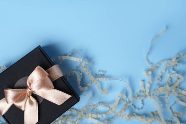 Hediye ya da hediye paketi ve yukarıdan mavi masa arkaplanındaki kağıt konfeti. Düz kompozisyon. Doğum günü kartı, anneler günü ya da düğün kartı..