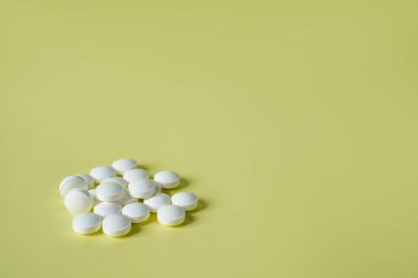 Beyaz hapların ilaç sarısı arka planı, makro. Uyuşturucu üretim arkaplanı, yakın plan. Sağlık ve ağrı için vitamin tableti. Tıbbi konsept.